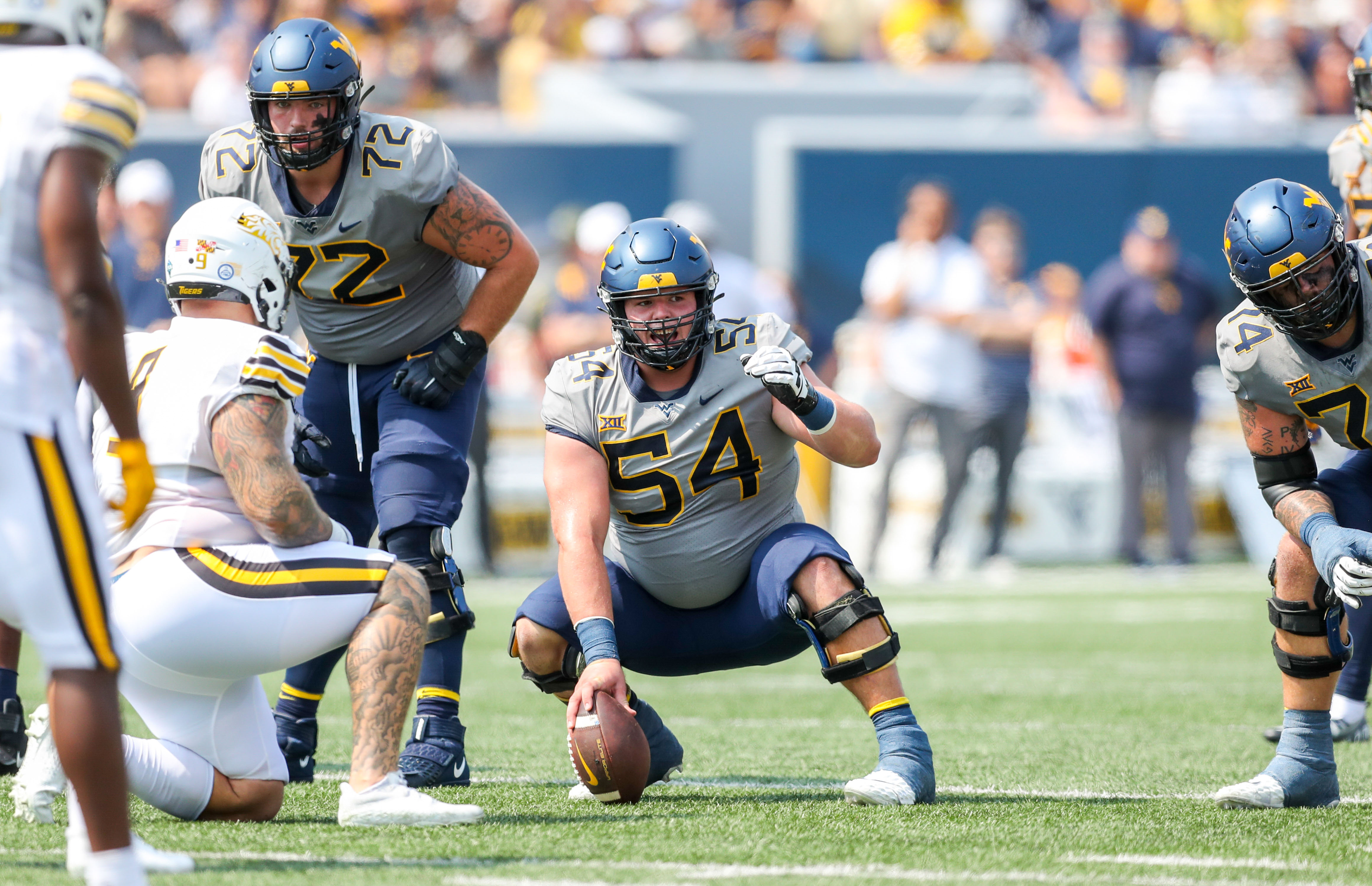 Zach Frazier bends down holding the football before a snap
